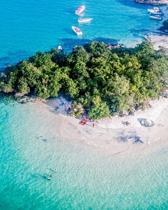 Vista de cima de ilha com banco de areia e água azul-turquesa, com barcos ao redor